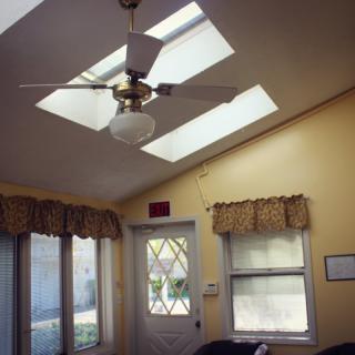 A bright room with skylights, a ceiling fan, and windows adorned with curtains.