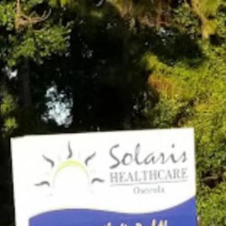 A sign for Solaris Healthcare surrounded by lush greenery.