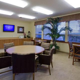 A well-lit meeting room with a central table, several chairs, and a television mounted on the wall.