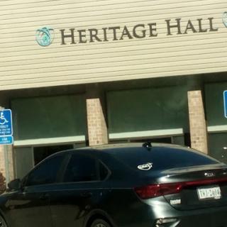 A view of Heritage Hall with a parked black car in front.