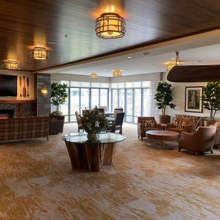 A modern and spacious lobby featuring comfortable seating, indoor plants, and ample natural light from large windows.
