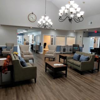 A spacious lobby area with comfortable sofas and chairs, illuminated by elegant chandeliers.