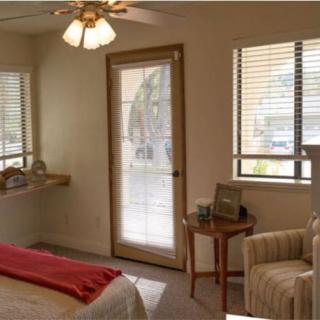 A cozy bedroom with a bed, chair, and natural light coming through the windows.