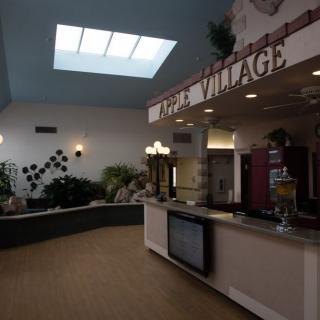 A spacious lobby area with a reception counter, skylight, and decorative plants.