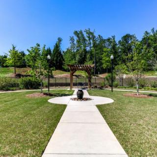 A well-maintained garden with a central pathway and lush greenery under a clear blue sky.