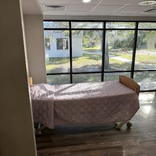 A hospital patient room featuring a bed and large windows allowing natural light to enter.