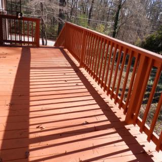 A wooden deck with railings casts long shadows in the sunlight.