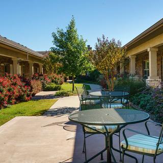A peaceful outdoor patio area with tables, chairs, and a landscaped garden path.