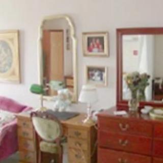 A cozy bedroom with a dresser, mirror, and decorative items.