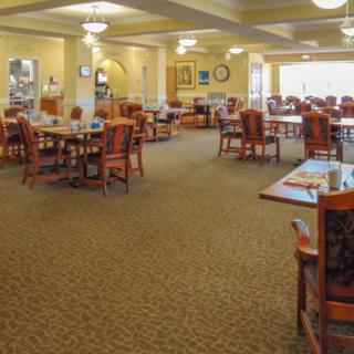 A spacious dining room with neatly arranged tables and chairs under warm lighting.