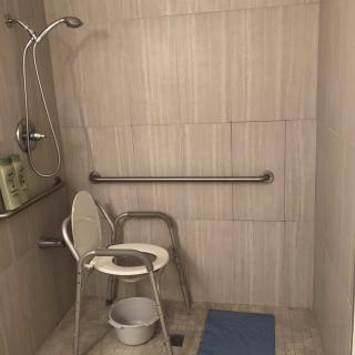Accessible shower area with a chair and grab bars.