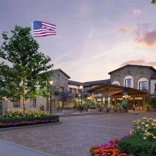 A beautifully landscaped entrance to a building at sunset, featuring an American flag and vibrant garden.