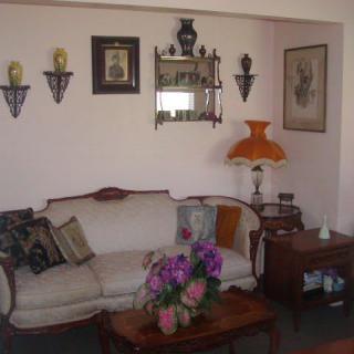 A cozy living room with vintage decor, featuring a sofa, colorful cushions, and a decorative table lamp.