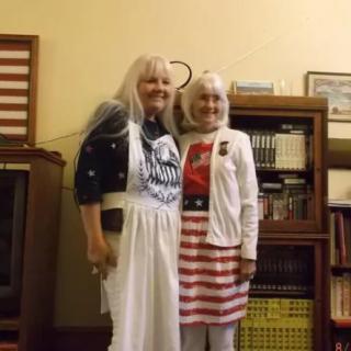 Two people in themed costumes standing in front of a bookshelf.