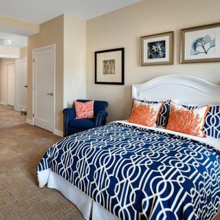 A modern bedroom with stylish bedding and framed artwork on the walls.