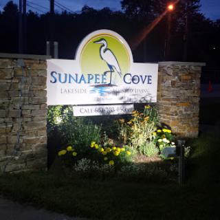 Entrance sign for Sunapee Cove illuminated at night.