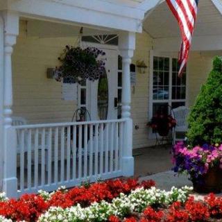 A charming porch with vibrant flowers and an American flag.