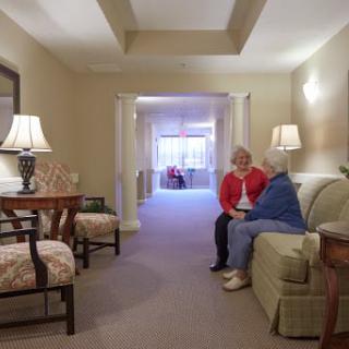 Two people sit and converse in a warmly lit living room.