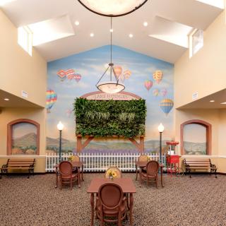 A brightly lit lobby featuring a mural with hot air balloons, skylights, and comfortable seating arrangements.