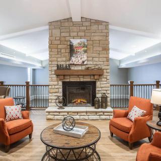 A cozy living room with a stone fireplace and orange armchairs.