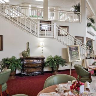 A well-decorated lobby area with a staircase, dining setup, and plants.