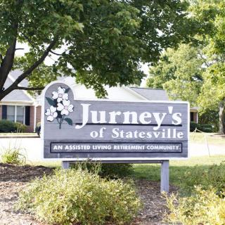 A sign for Jurney's of Statesville, an assisted living retirement community, surrounded by greenery.