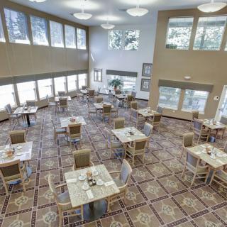 A spacious and modern dining area with multiple tables and large windows allowing natural light to fill the space.
