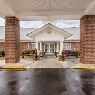 The front entrance of a brick building with outdoor seating and a covered driveway.