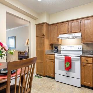 A cozy kitchen with wooden cabinets, a stove, and a nearby dining area.