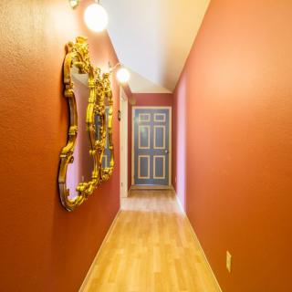 A vibrant hallway with red walls, a decorative mirror, and wooden flooring.