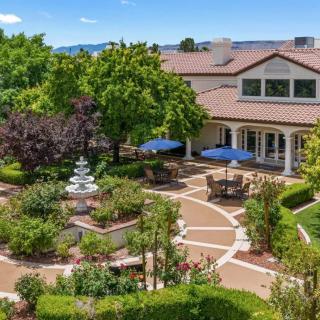 A beautifully landscaped garden with a fountain and outdoor seating area next to a large building.