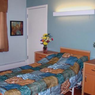 A neatly arranged bedroom with a single bed, colorful bedspread, bedside table, and wall decorations.