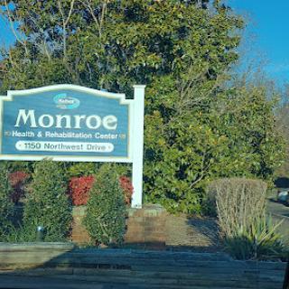 Welcome sign for Monroe, surrounded by lush greenery.