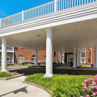A building entrance with white columns and landscaped surroundings under a clear blue sky.