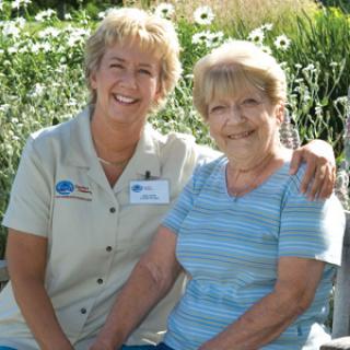 A cheerful moment shared between two women in a beautiful garden.