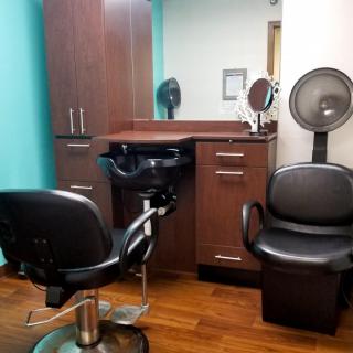 A cozy hair salon station with chairs, a mirror, and a sink.