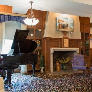 A cozy living room featuring a grand piano, fireplace, and armchair.