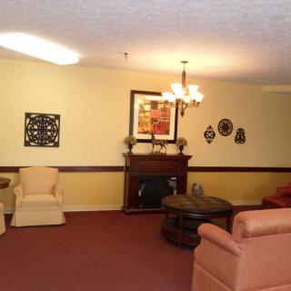 A cozy living room with sofas and armchairs, decorated with art pieces and a chandelier.