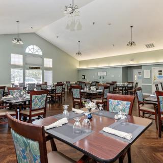A spacious dining room with neatly arranged tables and chairs, featuring elegant decor and large windows.