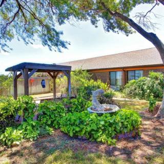 A scenic garden with a gazebo and fountain, surrounded by lush greenery next to a house.
