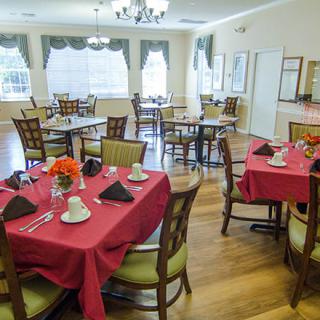 A well-decorated dining room featuring tables with red tablecloths and neatly arranged chairs.