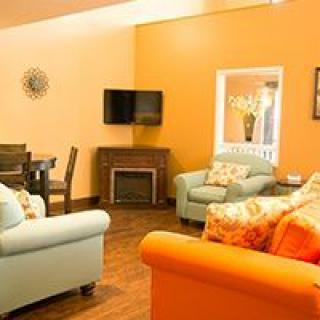 A cozy living room with vibrant orange walls, comfortable sofas, and a modern entertainment setup.