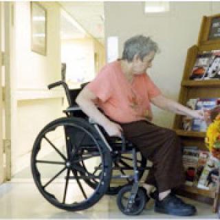 An elderly individual in a wheelchair engaged in an activity at a care facility.