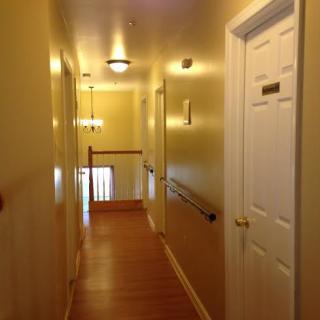 A warmly lit hallway with several doors and a wooden banister.