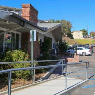 A view of a building with a brick chimney and a parking lot, featuring a ramp in the foreground under a clear blue sky.