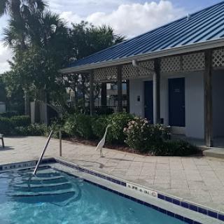 A serene pool area surrounded by lush greenery and a charming building.