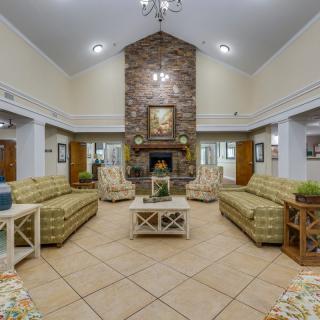 A cozy living room interior with sofas, armchairs, and a central fireplace.