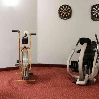A cozy exercise room featuring a stationary bike and fitness machine, with dartboards on the wall.
