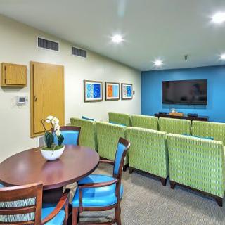 A modern living room with green chairs and a flat-screen TV.