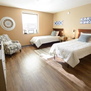 A spacious and well-lit bedroom featuring two beds and a cozy seating area.
